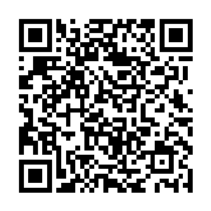 身穿一套绿色和服的金发男人正在一台仪器前忙碌着二维码生成